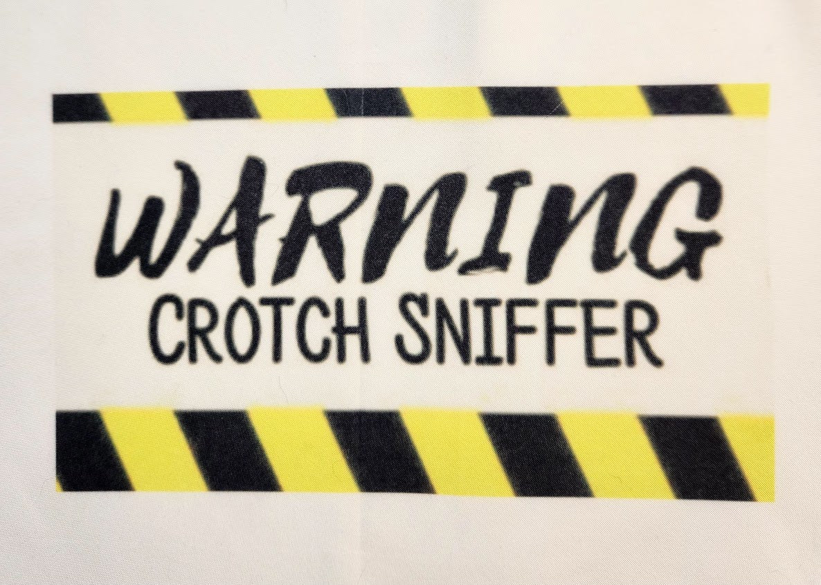 A pet bandana with a 'WARNING CROTCH SNIFFER' print in black and yellow caution stripes.