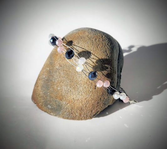 An elegant handcrafted bracelet with glass beads displayed on a rock.