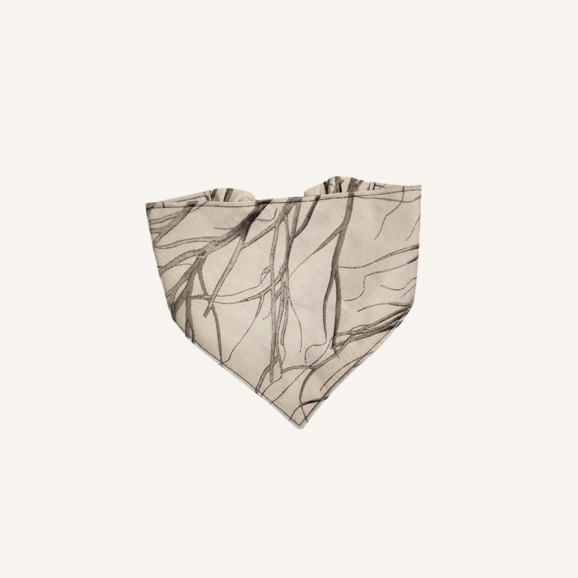 A beige bandana-style pet bandana featuring a dark brown sketch-style branch pattern, shown flat against a light cream background.