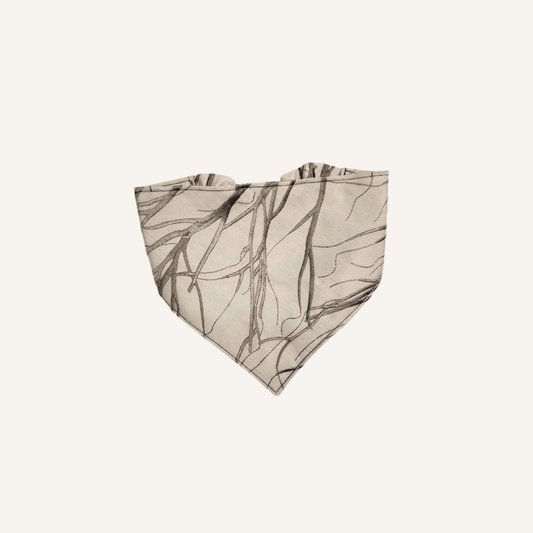 A beige bandana-style pet bandana featuring a dark brown sketch-style branch pattern, shown flat against a light cream background.