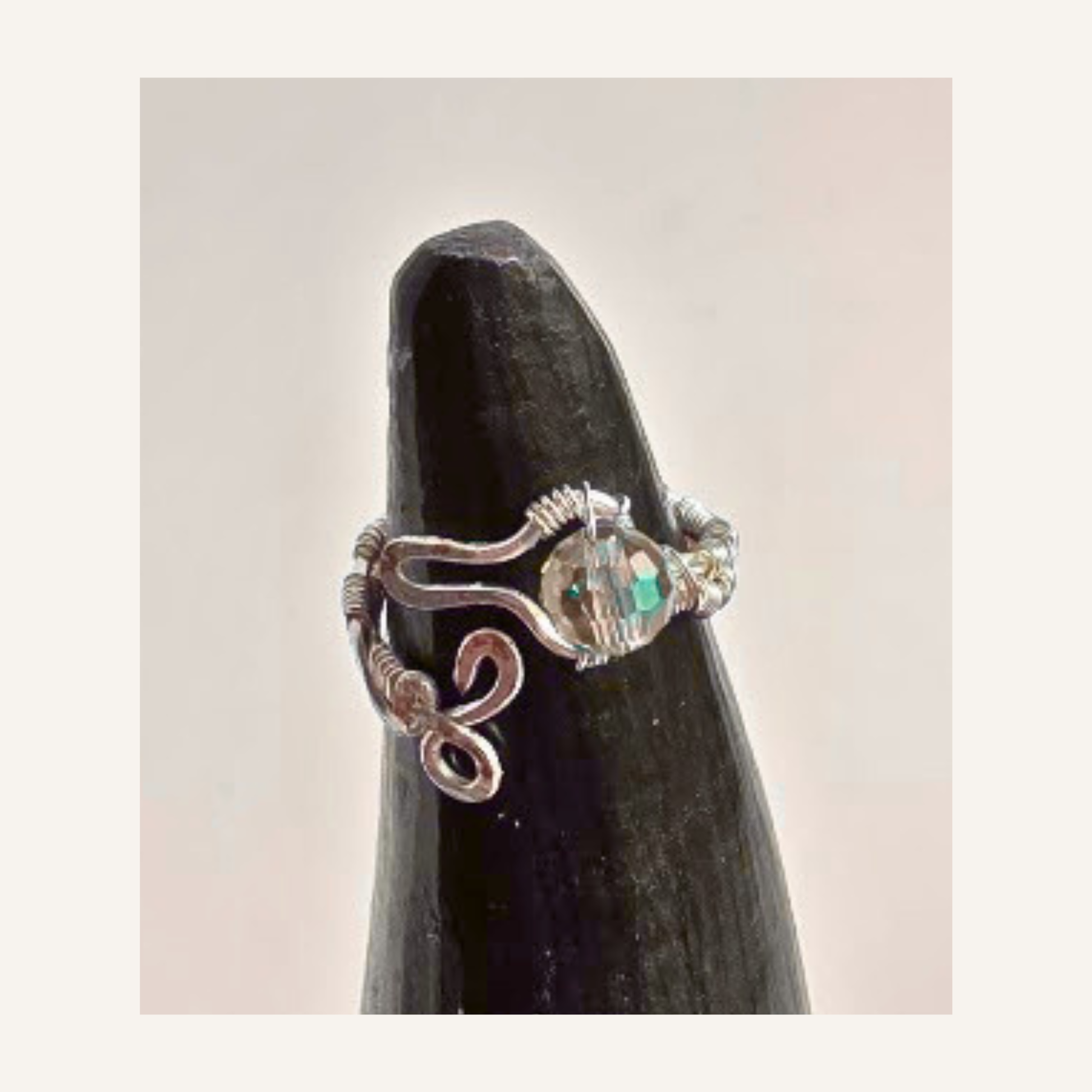 Shop a handmade adjustable silver-plated wire wrapped ring featuring a sparkling faceted crystal bead and artistic snake-inspired design. Made in Alberta.