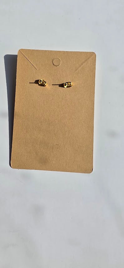 A pair of small gold stud earrings displayed on a brown kraft paper backing card against a light gray background.