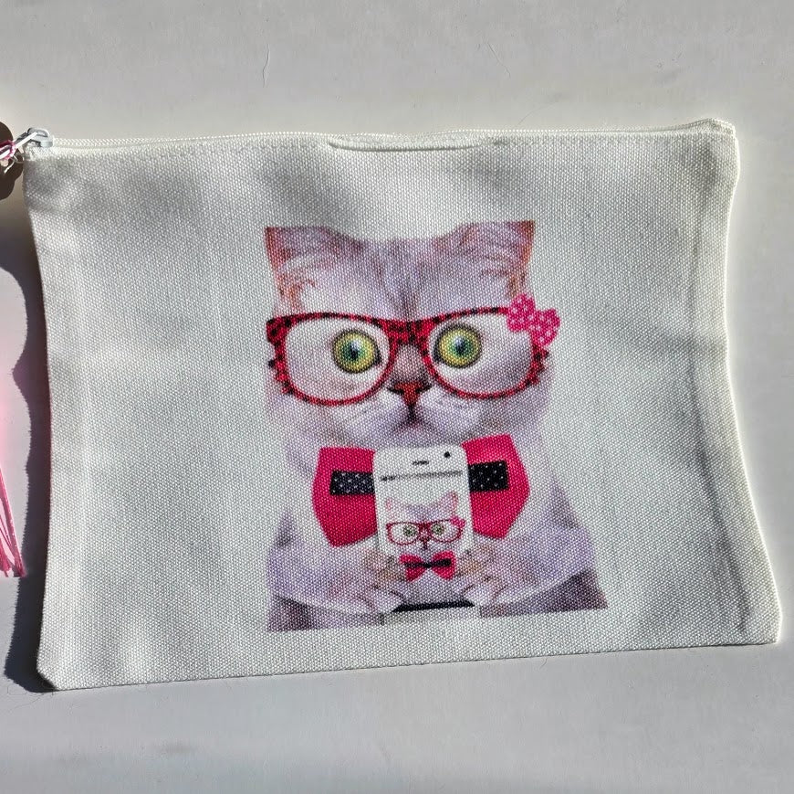 A white canvas zippered pouch featuring a printed graphic of a gray cat wearing red glasses, a red polka-dot bow tie, and holding a phone.