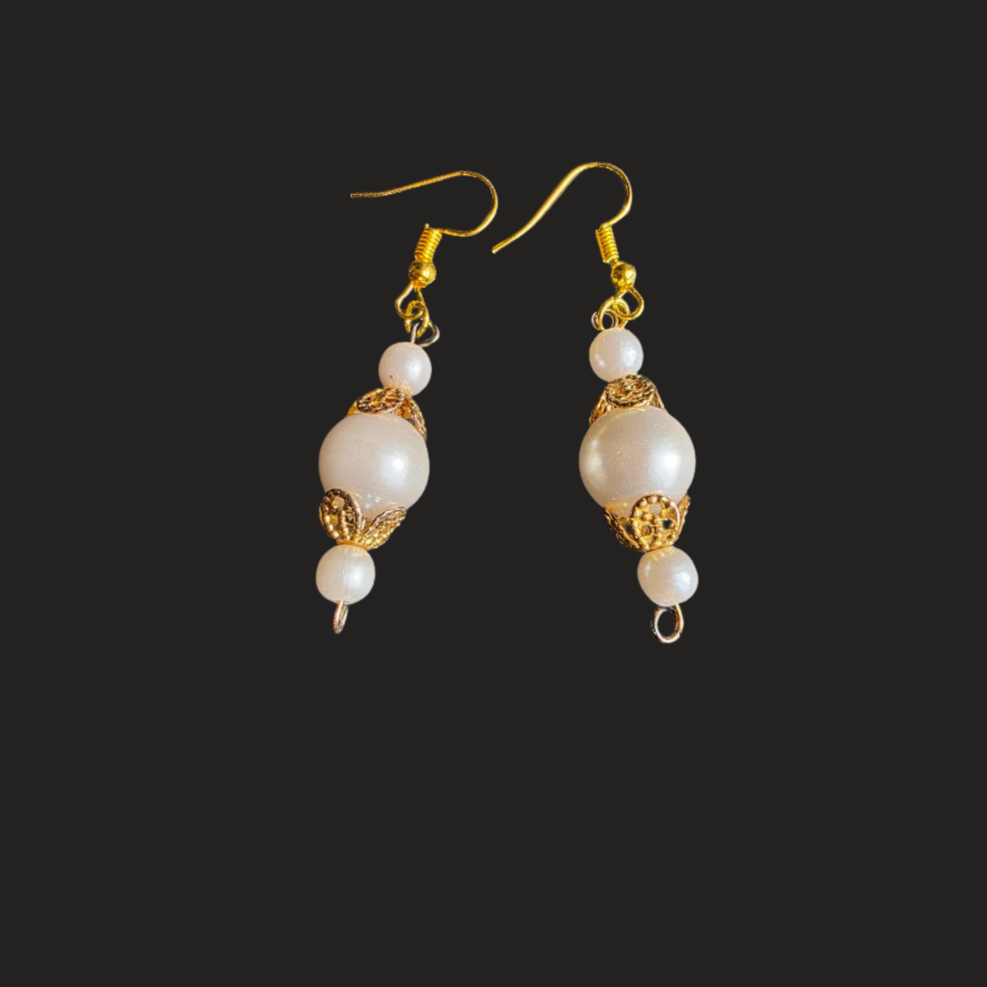 A pair of gold and white drop earrings with large pearl-like beads and ornate gold filigree details, shown against a solid black background. Handmade upcycled vintage faux pearl dangle earrings with gold-tone details