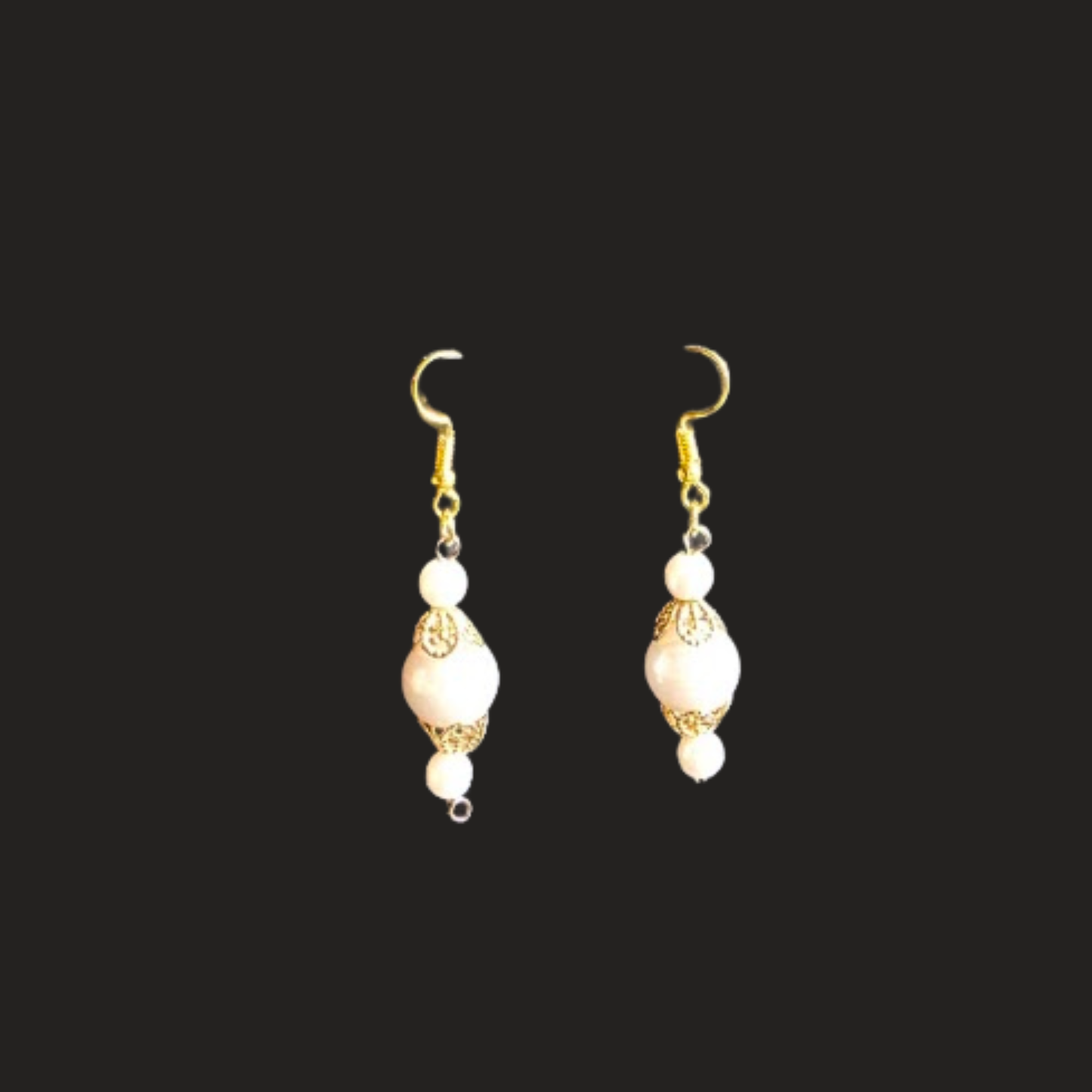 A pair of gold-tone dangle earrings with white pearl-like beads and small gold filigree details, shown against a solid black background.