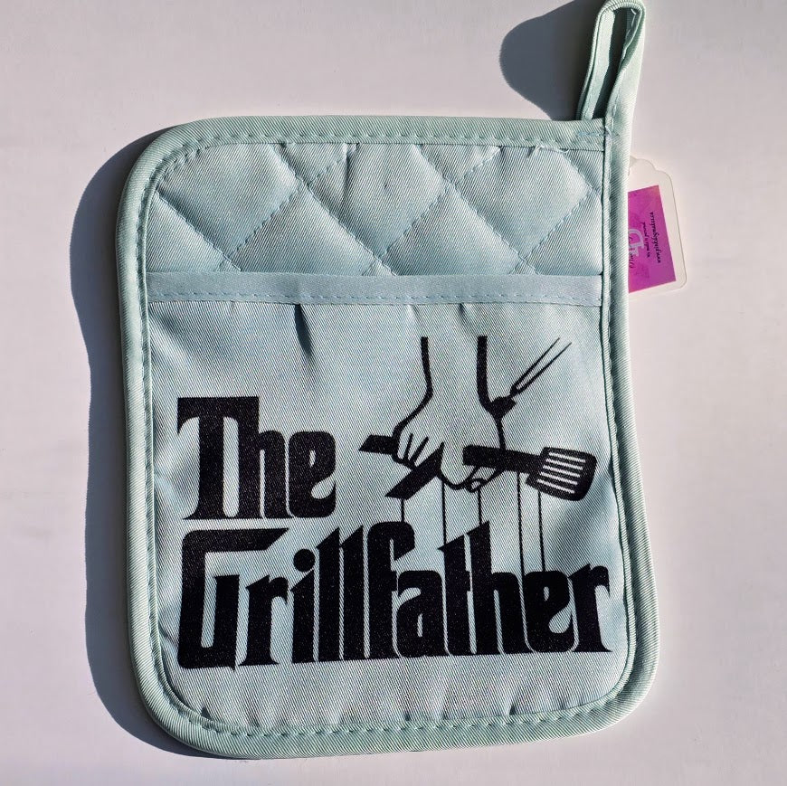 A light blue quilted pot holder with a black 'The Grillfather' graphic, displayed on a white background with a small purple tag attached.
