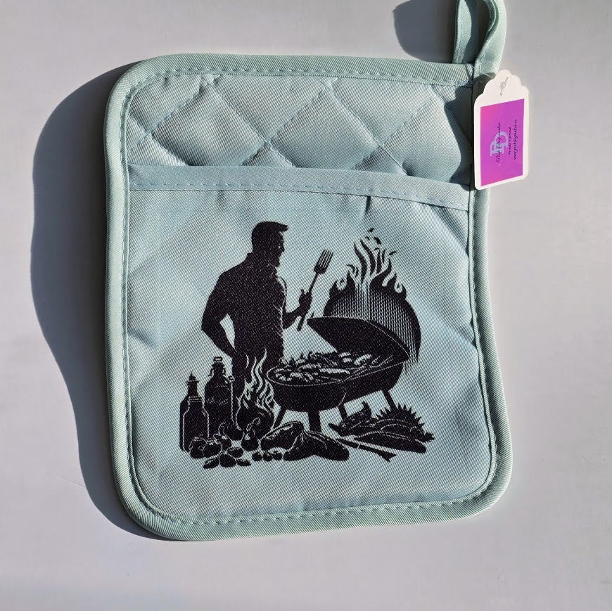 A light blue quilted pot holder with a black graphic of a man grilling, featuring a front pocket and a hanging purple brand tag.